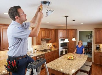 Electrician installing recessed lighting in a kitchen ceiling