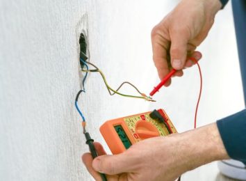 Close-up of a gloved hand testing exposed wiring with a probe