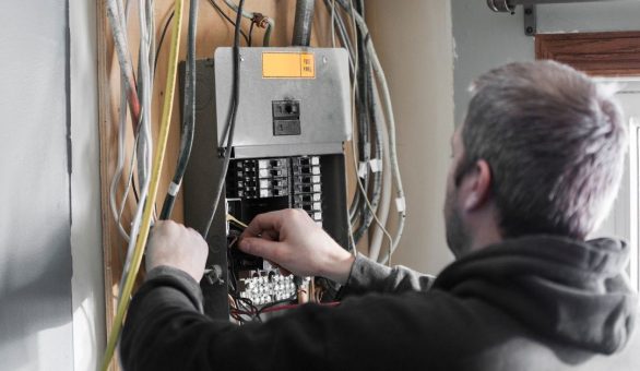 Electrician working inside an open circuit panel