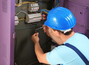 Electrician in a hard hat working on an electrical panel