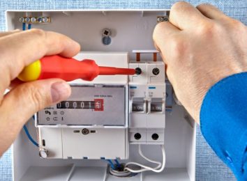 Close-up of hands adjusting an electric meter with a screwdriver