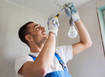 Electrician looking up while installing an overhead light bulb