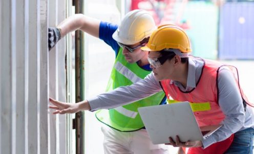 Two commercial electricians reviewing an installation with a laptop on site