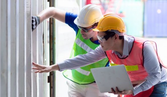Two commercial electricians reviewing an installation with a laptop on site