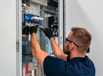 Electrician working inside an open circuit breaker panel