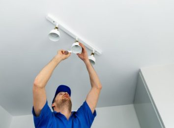 Electrician installing recessed lighting fixtures in a ceiling