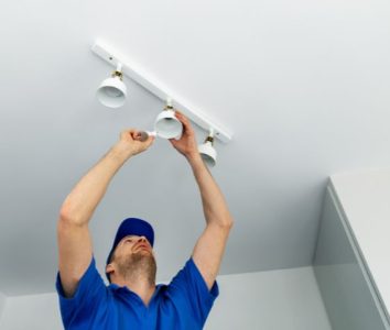 Electrician installing recessed lighting fixtures in a ceiling